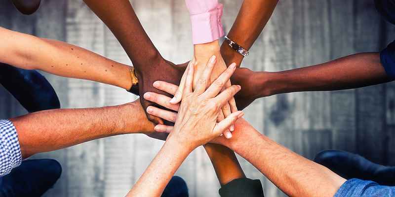 Multiple people putting their hands together.