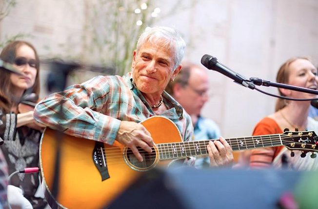 Image of Jai Uttal playing guitar outside