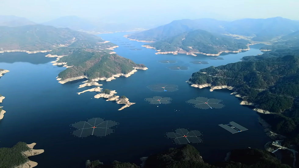 绿色山丘起伏绵延的蓝宝石般的湖面上,漂浮着几座花形太阳能光伏组件。